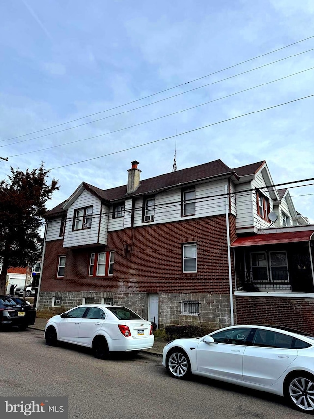 view of property featuring brick siding and a chimney