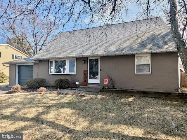 view of front of property with a front yard, a garage, brick siding, and roof with shingles