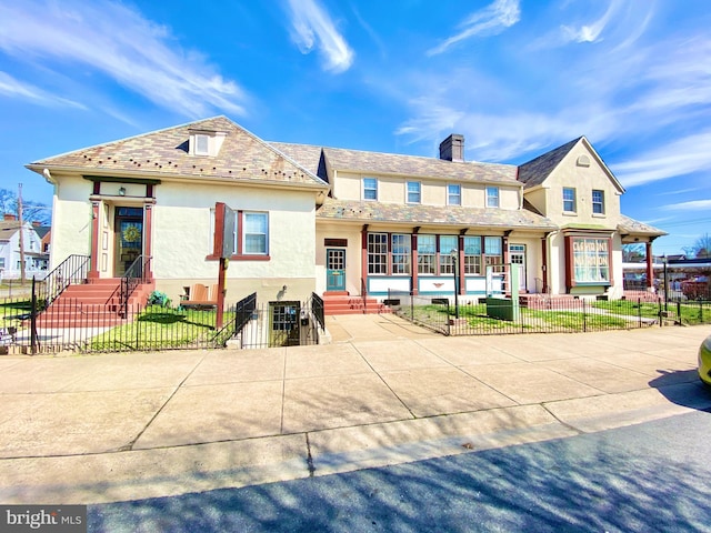 view of front of home featuring a fenced front yard, a chimney, and stucco siding