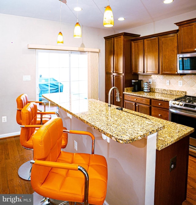 kitchen featuring appliances with stainless steel finishes, backsplash, light stone counters, and dark wood-style floors