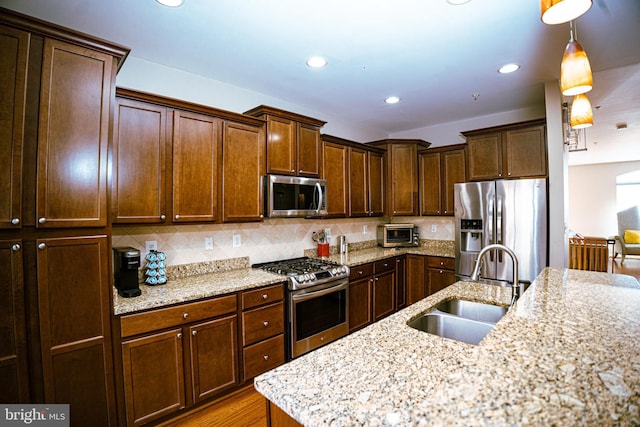 kitchen with recessed lighting, a sink, appliances with stainless steel finishes, backsplash, and decorative light fixtures