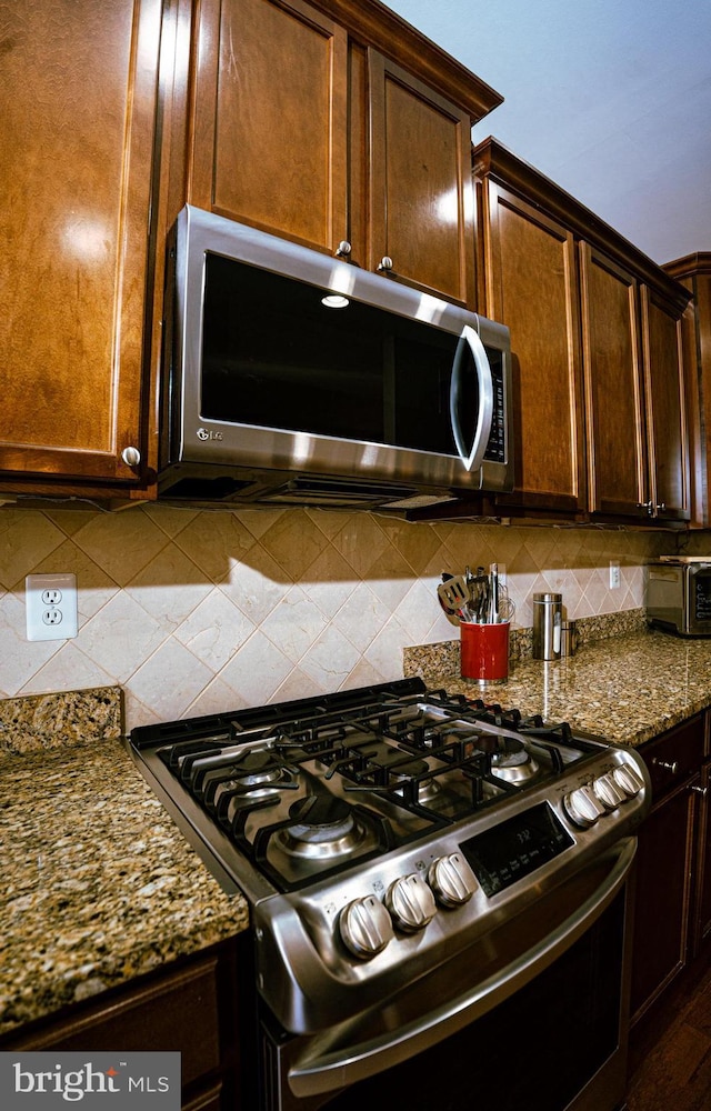 kitchen with tasteful backsplash, stainless steel appliances, and dark stone countertops