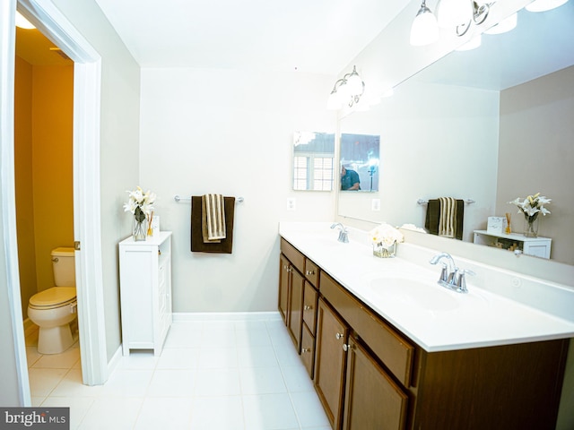 full bathroom featuring toilet, a sink, baseboards, and double vanity