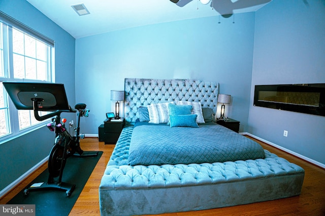 bedroom featuring baseboards, visible vents, ceiling fan, and wood finished floors