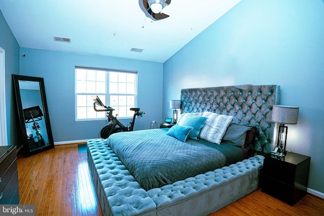 bedroom with lofted ceiling, baseboards, visible vents, and wood finished floors