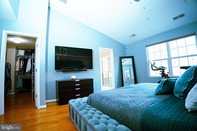 bedroom featuring vaulted ceiling, a spacious closet, wood finished floors, and visible vents