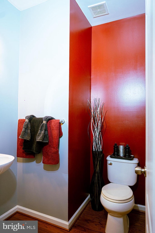 half bathroom featuring baseboards, visible vents, toilet, and wood finished floors