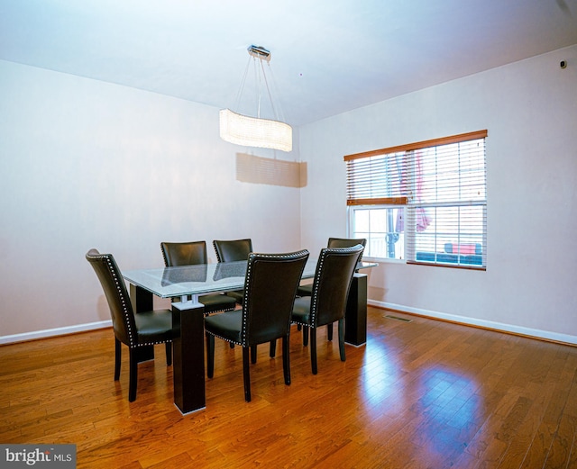 dining space with visible vents, baseboards, and wood finished floors