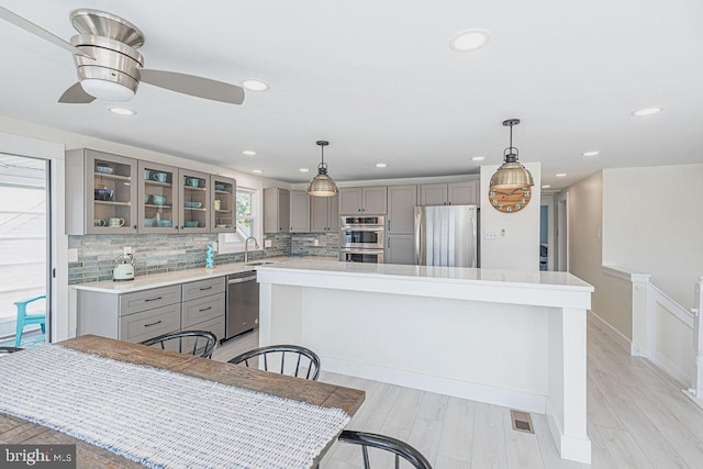 kitchen featuring stainless steel appliances, backsplash, and gray cabinets