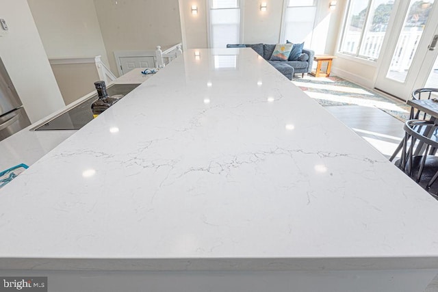 interior details featuring light stone counters, black electric cooktop, and wood finished floors