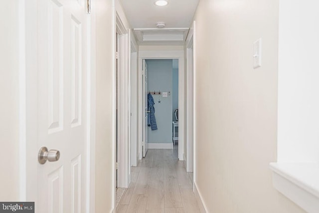 hall featuring attic access, light wood-style floors, and baseboards