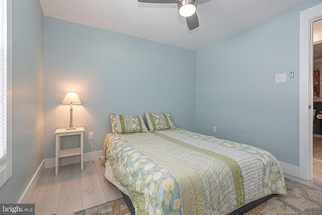 bedroom featuring a ceiling fan, baseboards, and wood finished floors