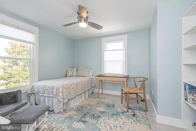 bedroom with light wood-type flooring, ceiling fan, and baseboards