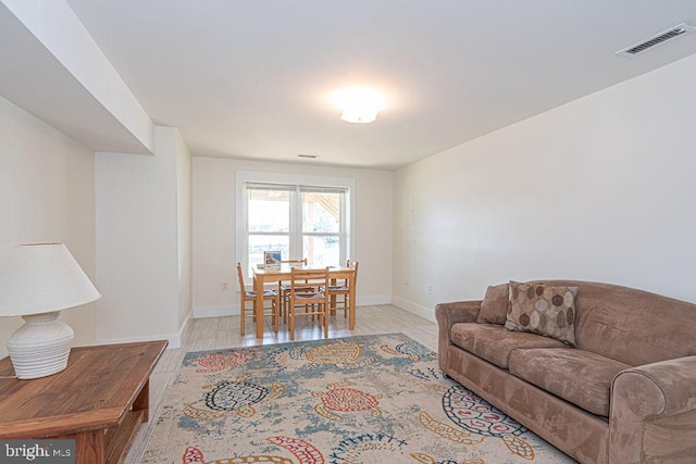 living room featuring wood finished floors, visible vents, and baseboards