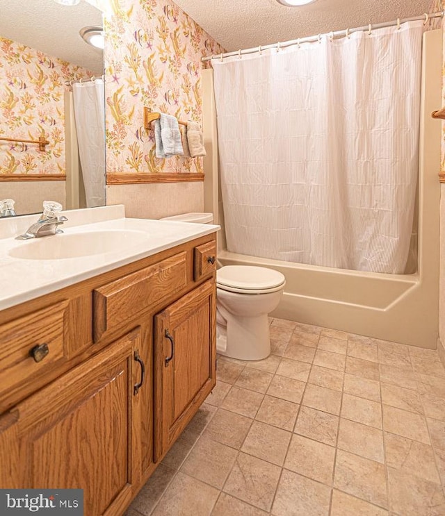 bathroom with a textured ceiling, wainscoting, toilet, and wallpapered walls