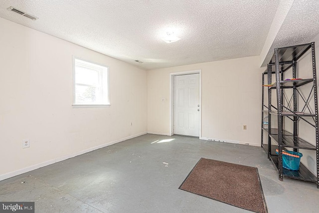 spare room with baseboards, visible vents, concrete flooring, and a textured ceiling