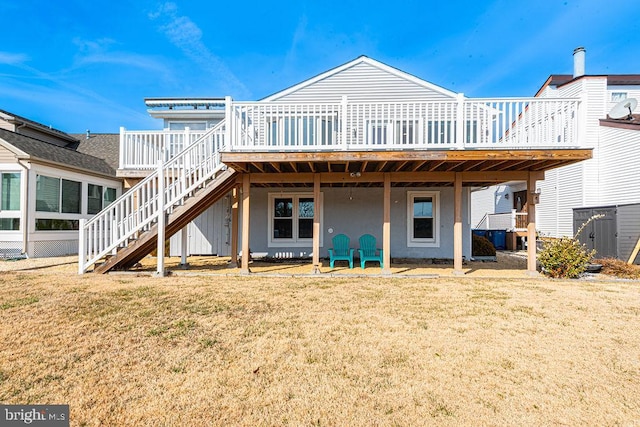 back of property featuring a lawn, a wooden deck, and stairs