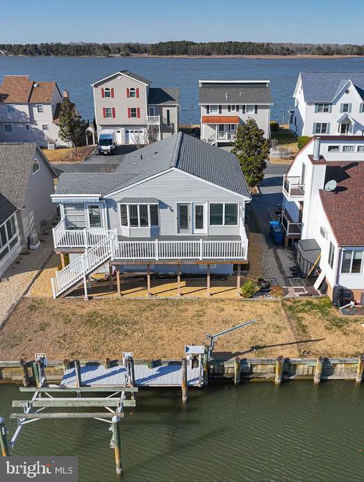 rear view of house with boat lift, a residential view, metal roof, and a deck with water view