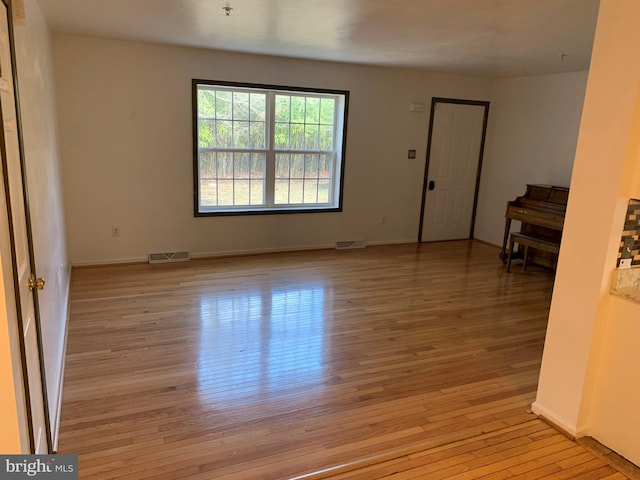 spare room featuring baseboards, visible vents, and light wood-style floors