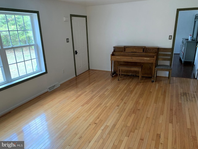 living area with light wood-type flooring, visible vents, and baseboards