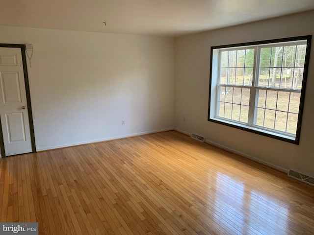 spare room featuring light wood-type flooring, baseboards, and visible vents