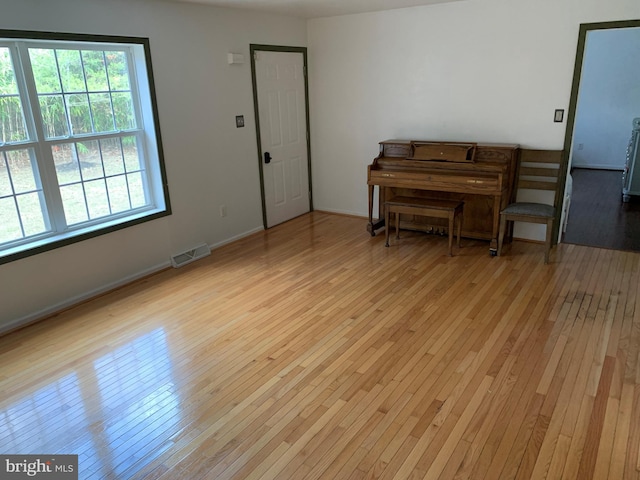 living area with hardwood / wood-style floors, visible vents, and baseboards