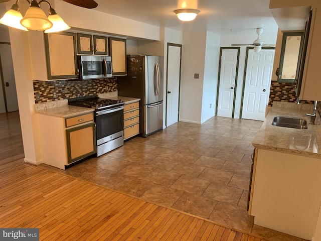 kitchen featuring ceiling fan, stainless steel appliances, backsplash, and a sink