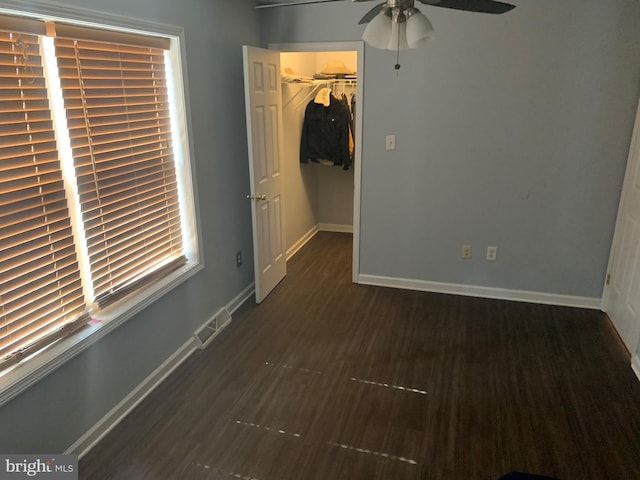 unfurnished bedroom featuring a walk in closet, a closet, visible vents, wood finished floors, and baseboards