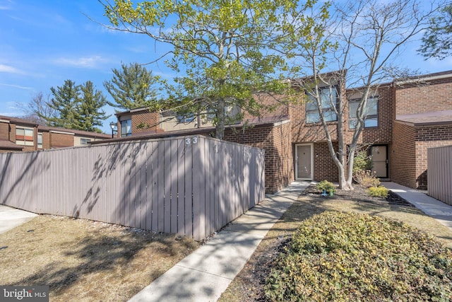 view of front of home with brick siding and fence