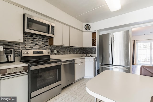 kitchen featuring backsplash, appliances with stainless steel finishes, and a sink