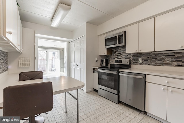 kitchen featuring decorative backsplash, appliances with stainless steel finishes, white cabinetry, and light countertops