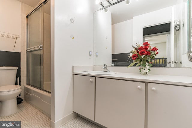 bathroom featuring tile patterned flooring, toilet, vanity, and enclosed tub / shower combo