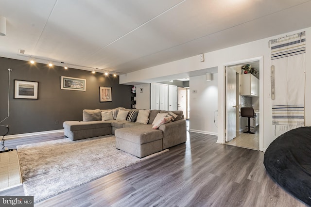 living room featuring dark wood-type flooring, track lighting, visible vents, and baseboards