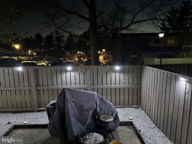 patio at night with area for grilling and a fenced backyard