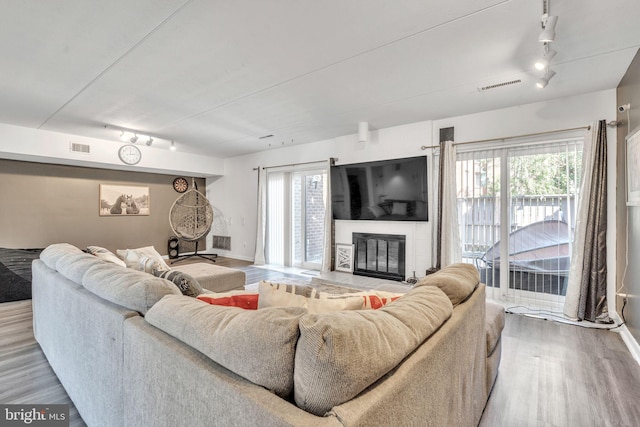 living area with a wealth of natural light, visible vents, a large fireplace, and wood finished floors