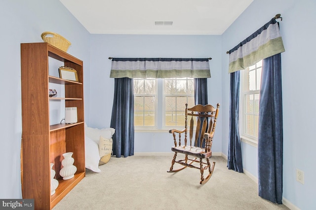 living area with a wealth of natural light, visible vents, carpet flooring, and baseboards