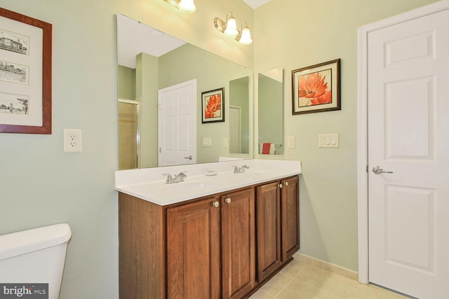 bathroom featuring tile patterned flooring, double vanity, toilet, and a sink