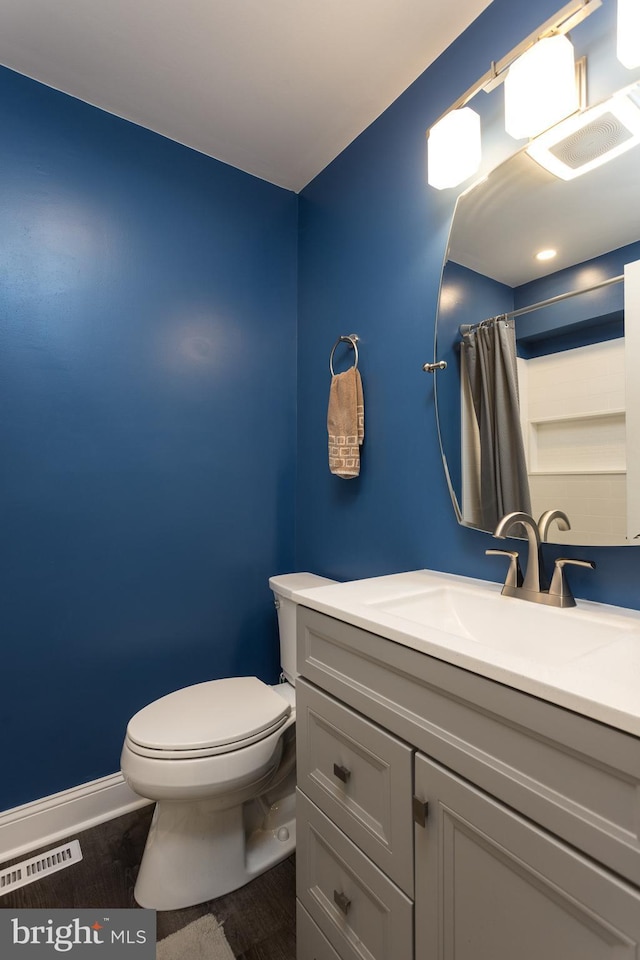 full bath featuring toilet, wood finished floors, vanity, visible vents, and baseboards