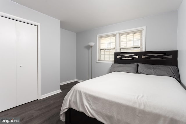 bedroom featuring dark wood-style floors, a closet, and baseboards