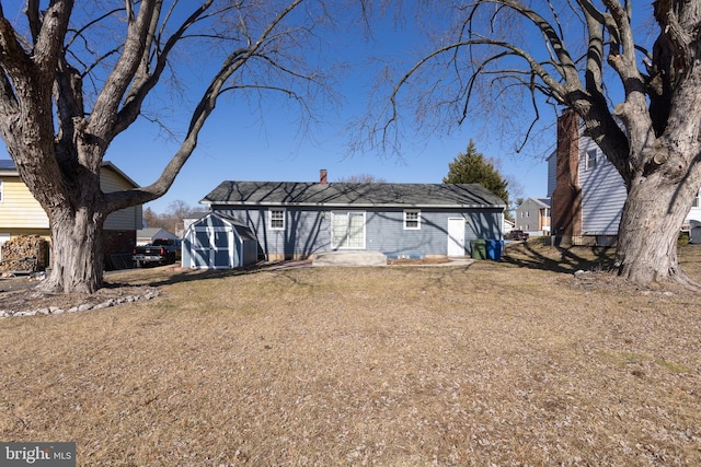 rear view of house with a storage shed, a yard, and an outbuilding