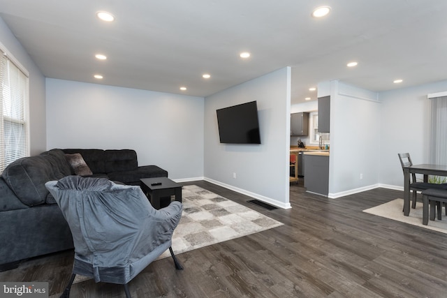 living area with baseboards, dark wood-type flooring, and recessed lighting