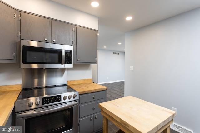 kitchen featuring stainless steel appliances, recessed lighting, visible vents, gray cabinetry, and wood counters