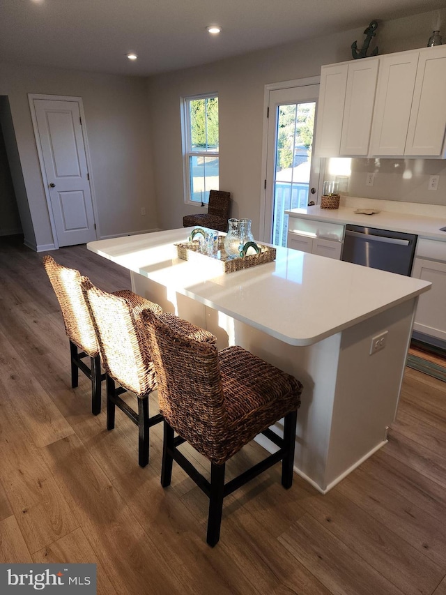 kitchen with a kitchen island, white cabinetry, stainless steel dishwasher, and wood finished floors