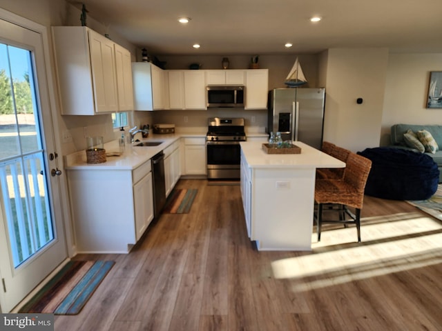 kitchen with a breakfast bar area, light countertops, appliances with stainless steel finishes, a sink, and a kitchen island