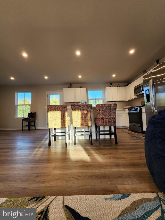 kitchen featuring dark wood-style floors, white cabinetry, appliances with stainless steel finishes, and a wealth of natural light