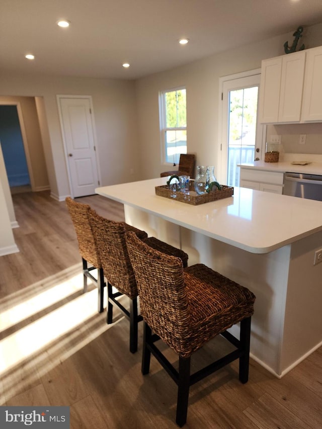 kitchen featuring a breakfast bar area, light wood-style flooring, recessed lighting, white cabinets, and light countertops