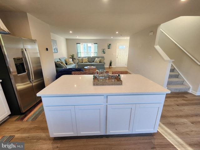 kitchen featuring stainless steel fridge, white cabinets, wood finished floors, and recessed lighting