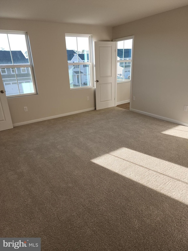 carpeted spare room featuring plenty of natural light and baseboards