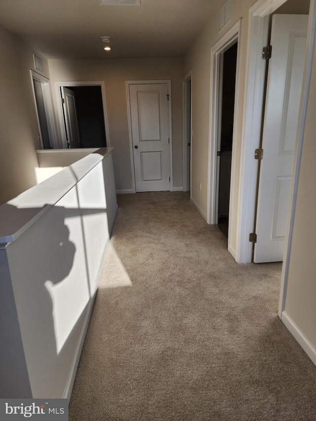 hallway with carpet flooring, visible vents, and baseboards