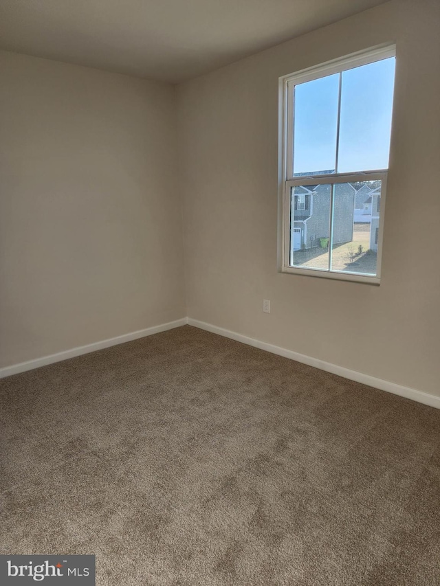 unfurnished room featuring carpet floors and baseboards